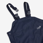 A close-up of Muddy Puddles' navy Puddleflex dungarees. The waterproof, fleece-lined trousers feature adjustable straps and reflective logo.